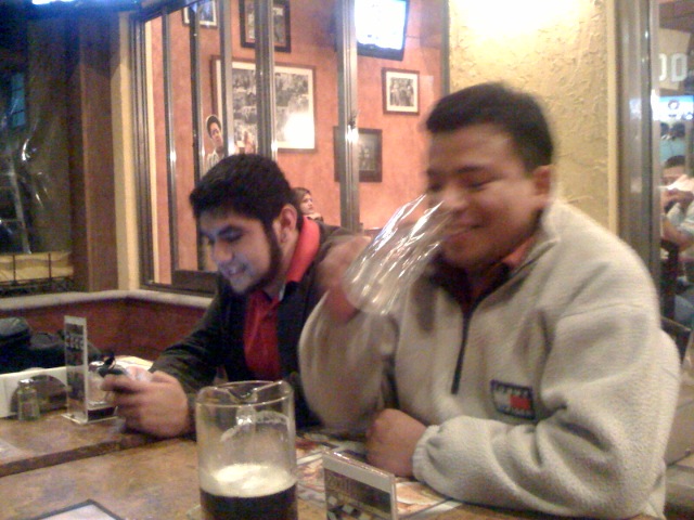 two men sitting at a table with glasses of beer