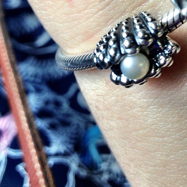 a woman is wearing a ring made of sterling and a pearl