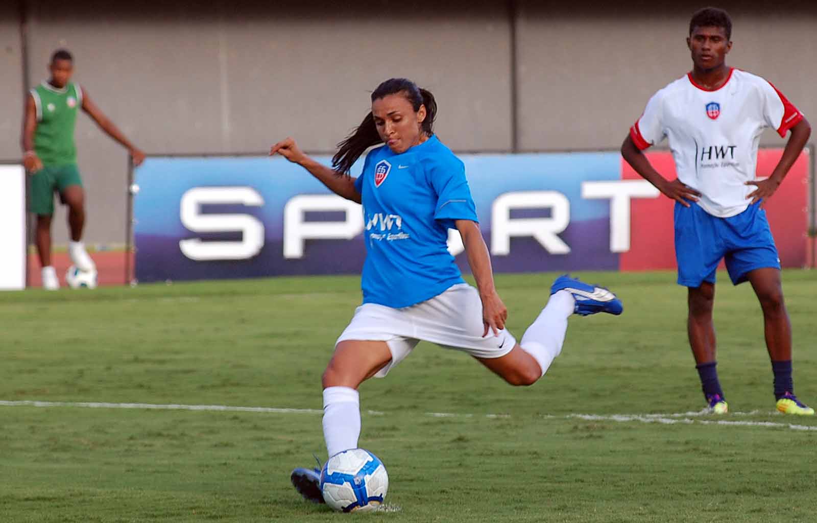 a young woman kicking the ball towards a goal