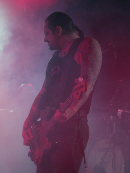 a man with long hair and tattoos on his arm playing bass guitar