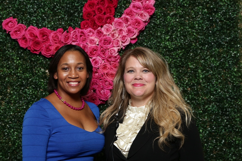 two women are posing for a picture in front of a floral wall