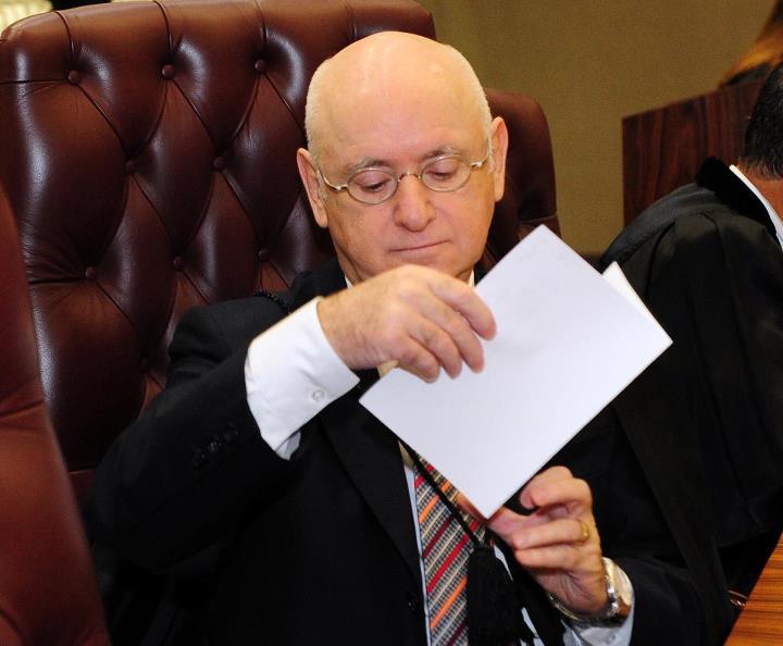 a judge in court sitting at the table with his hand on the paper