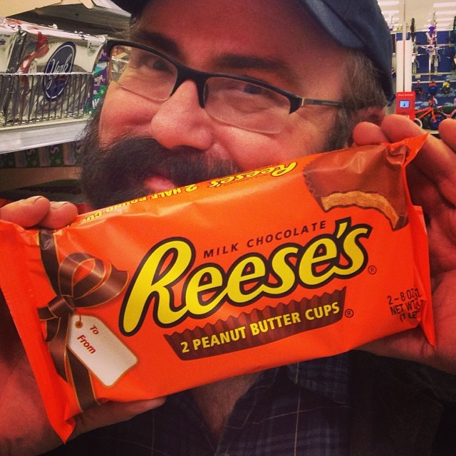 a man holding up an orange reese reese chocolate bar