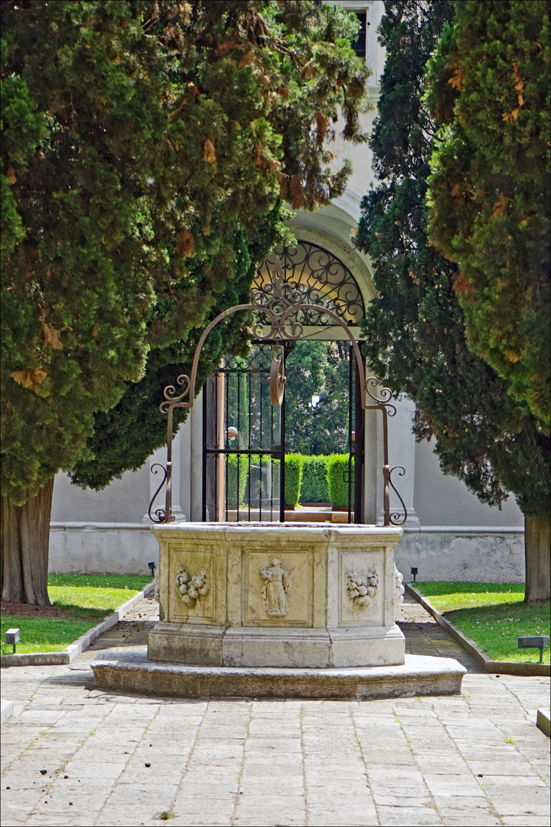 there is an elegant fountain surrounded by trees and shrubs
