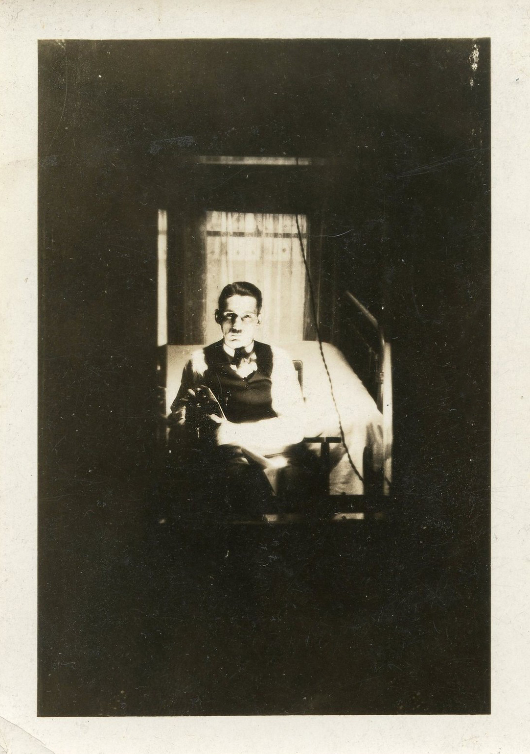 a young person sitting by a window holding a teddy bear