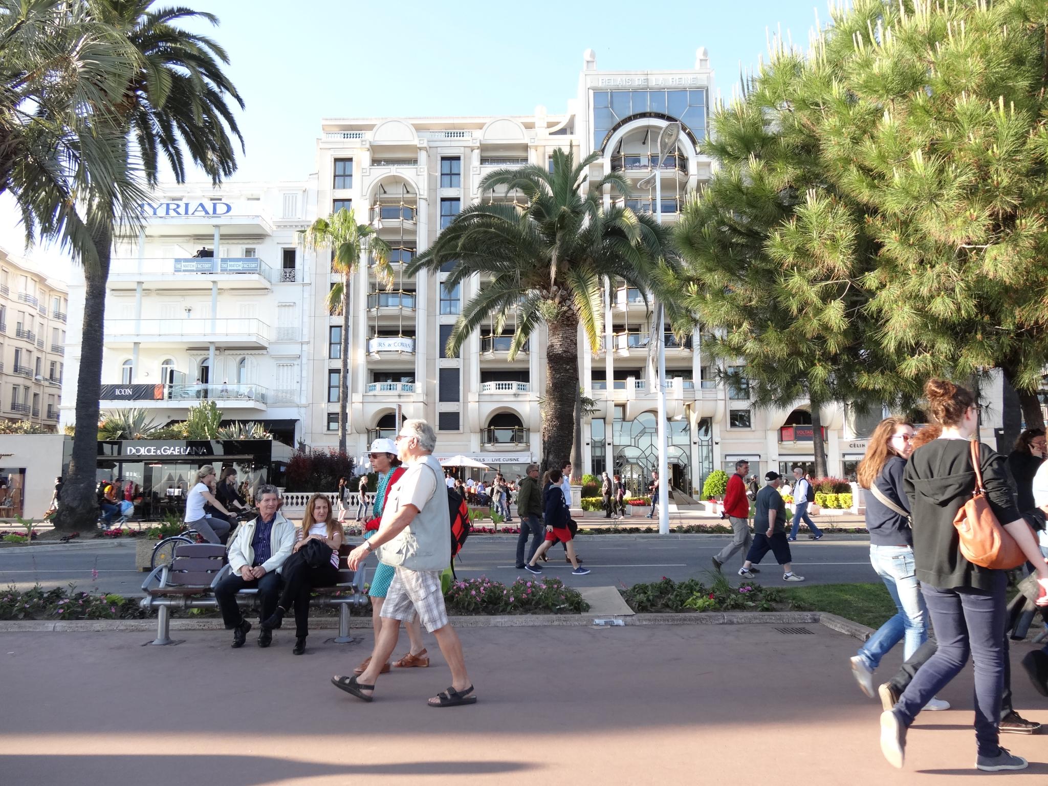 a group of people walk through the city with palm trees