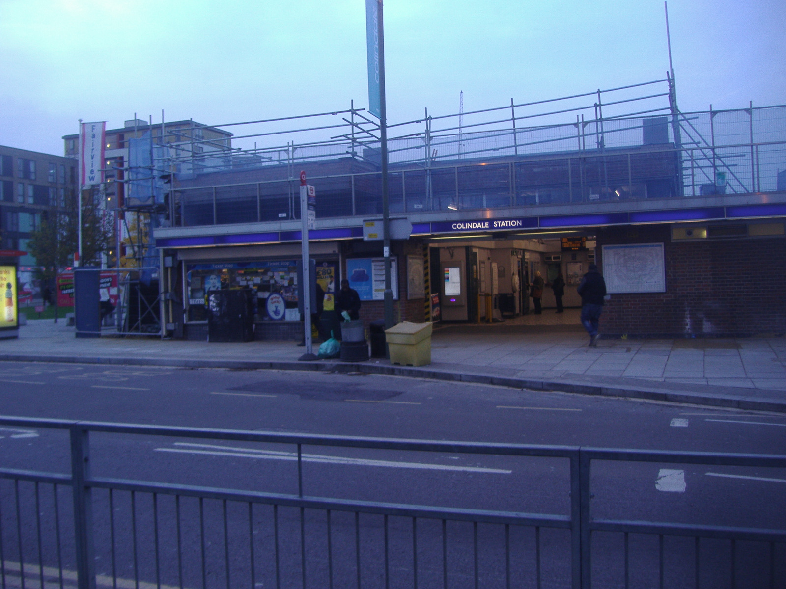 two people are walking past the empty bus stop