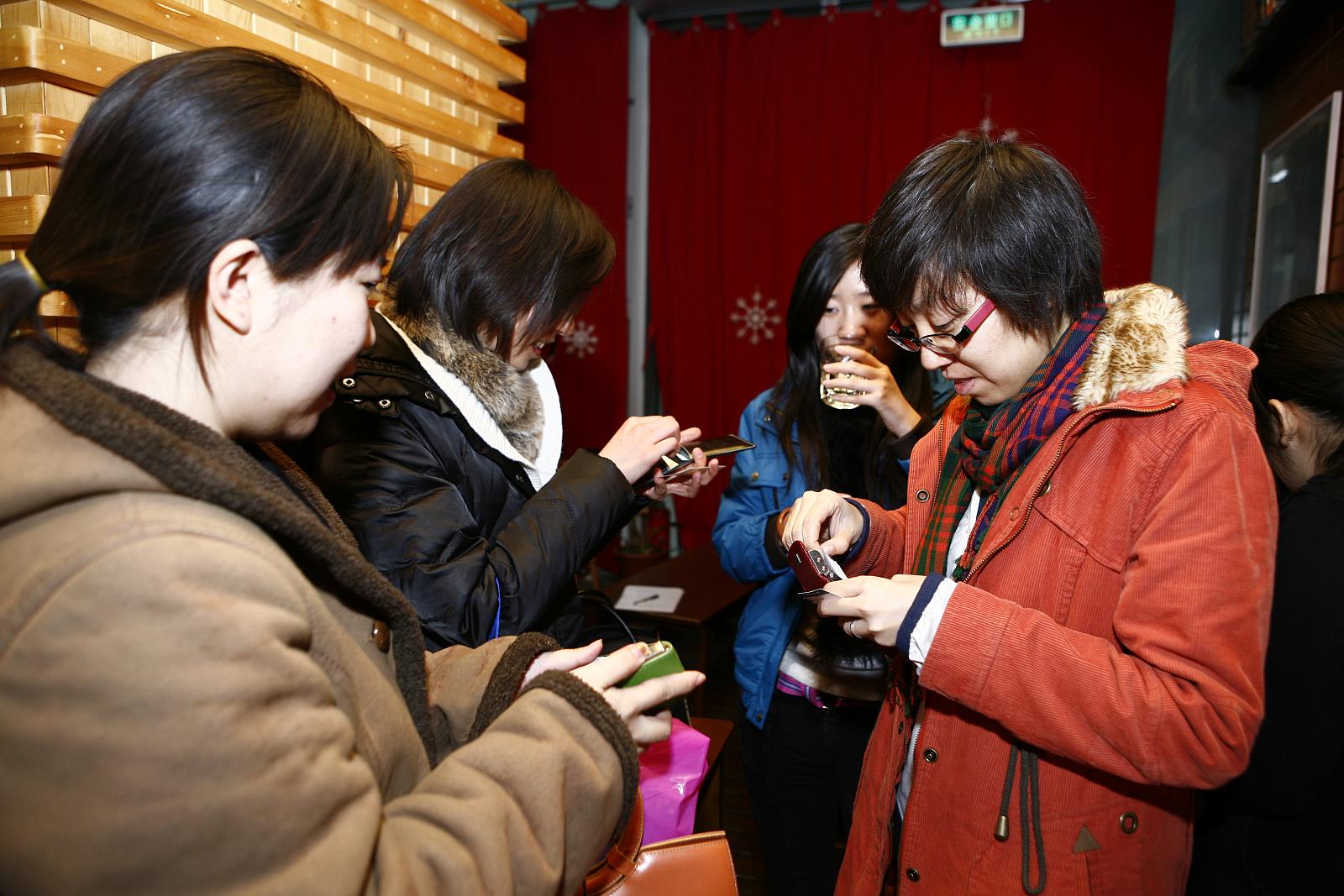 woman looking at her cell phone while others stand in the background