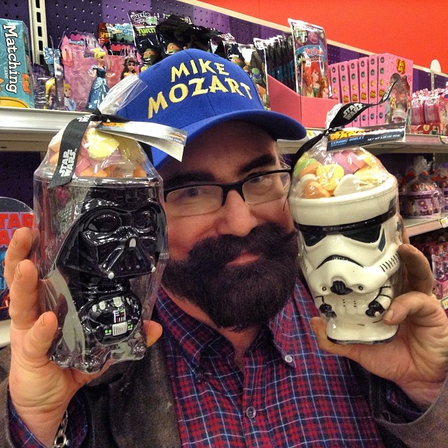 a man holding up a star wars figurine and a helmet in front of a store