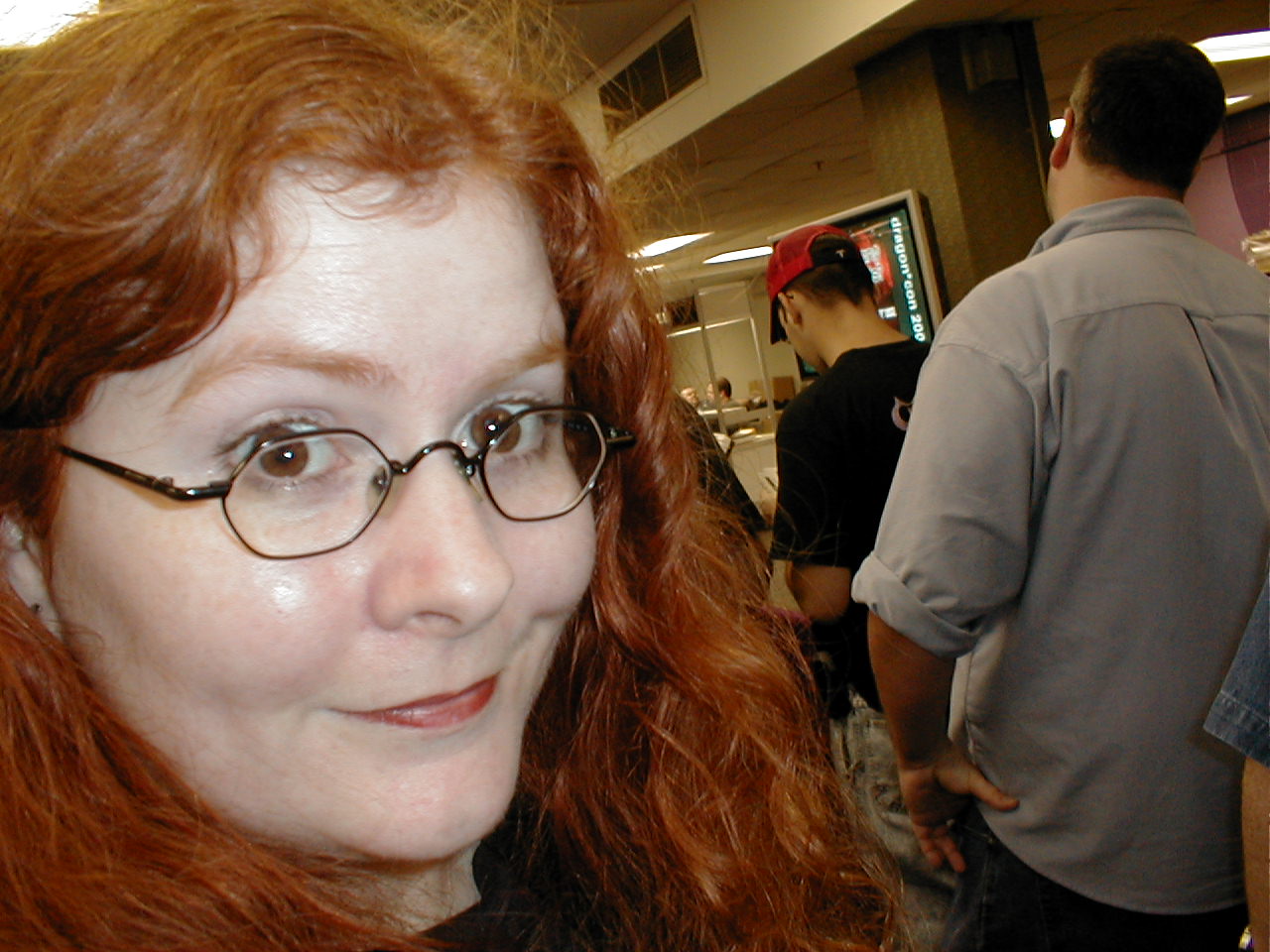 a young woman wearing glasses standing next to people