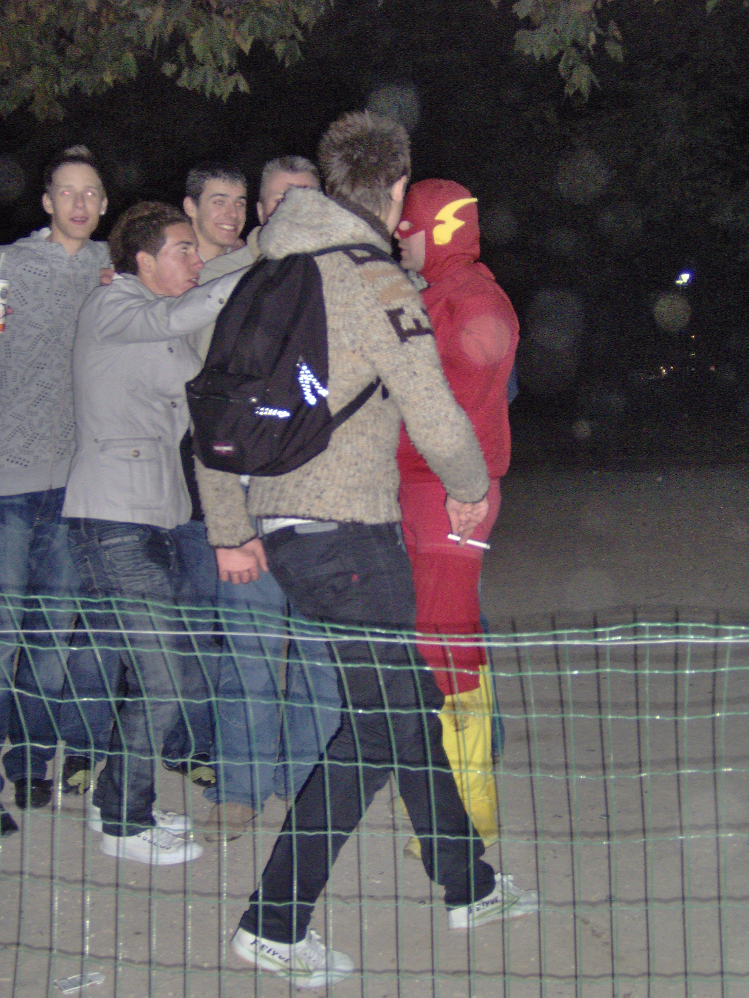 people standing behind a fence at night time