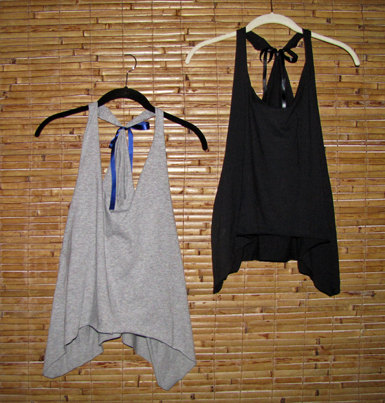 two tanks tops hanging from clothes hooks and bamboo wall