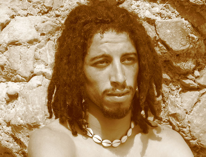 a man with dreadlocks and  on in front of a rock wall