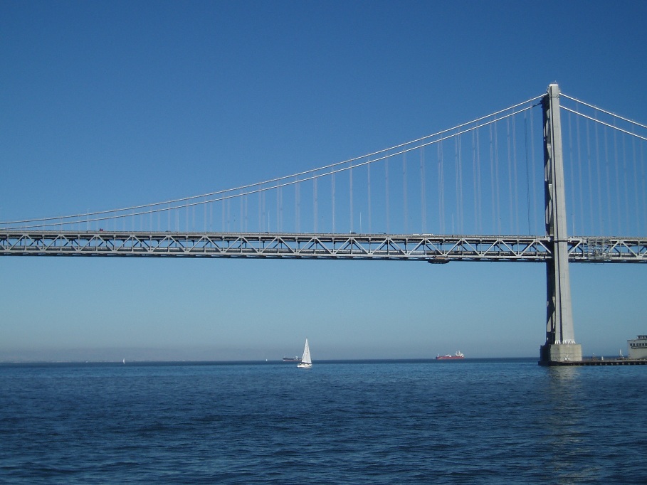 a sailboat is under the bridge in the ocean