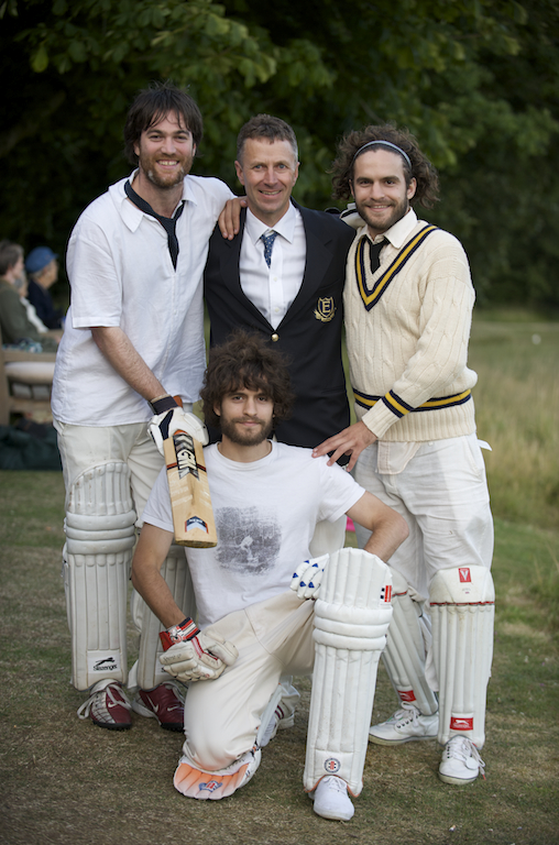 four men are posing for a pograph wearing their cricket uniform