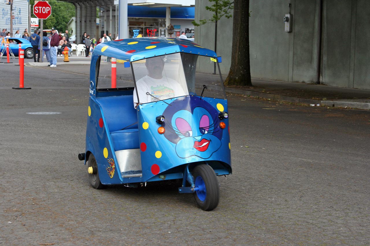a little boy driving a three wheeled blue toy truck