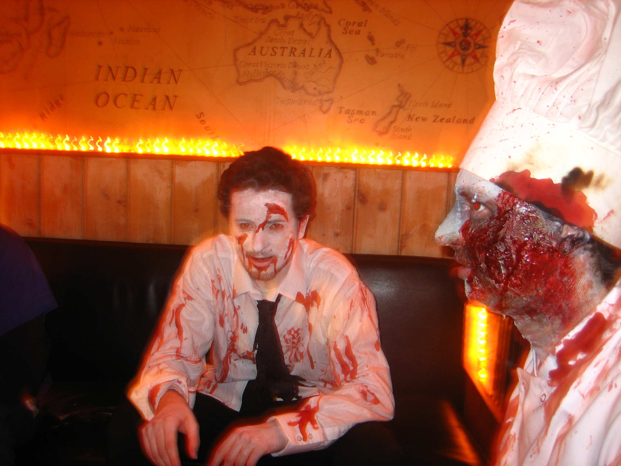 a man dressed up in zombie makeup sitting next to an zombie