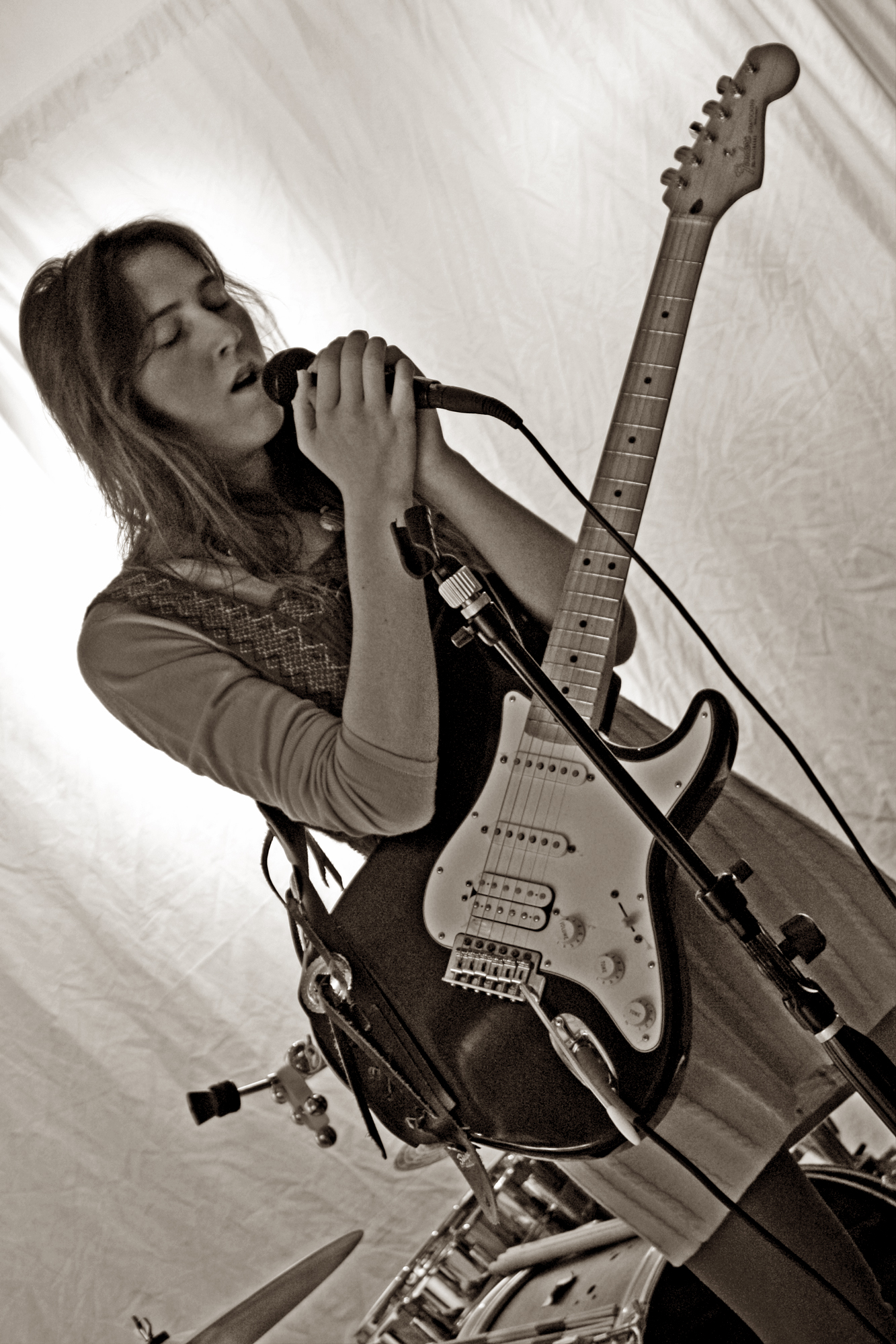 a woman is playing a guitar and singing into a microphone