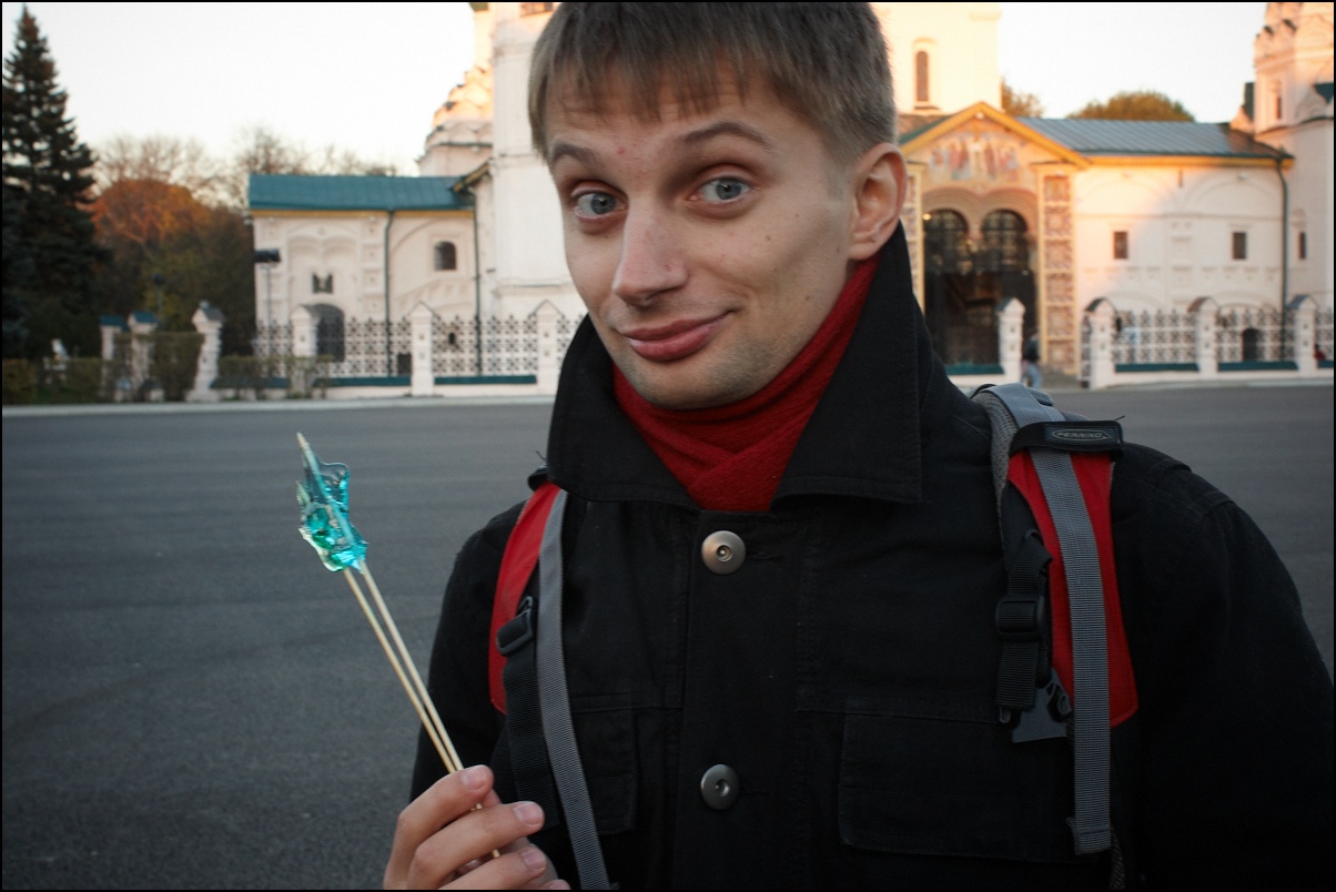 man in jacket pointing to the camera and holding up soing