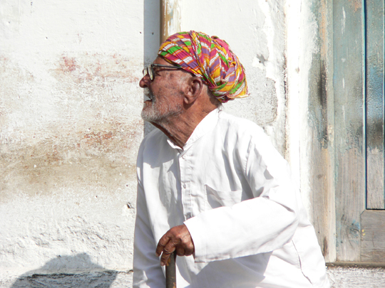 a man with a turban standing against a wall