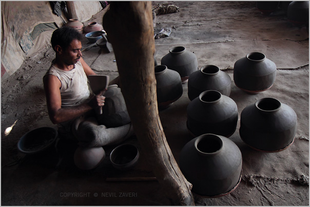 a woman with a laptop sitting next to a large pile of clay jars