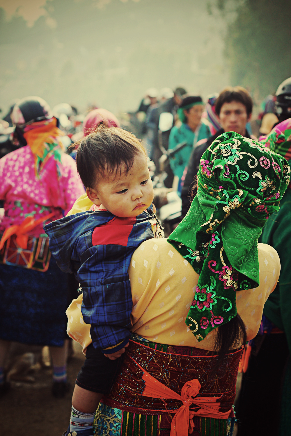 the little child is wearing a colorful headdress