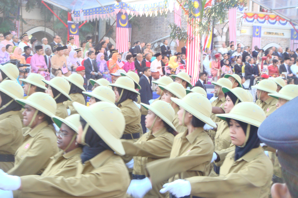 women dressed in uniform and hats sitting in rows with a crowd