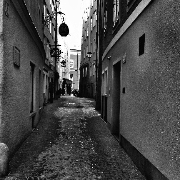 a narrow alley with tall buildings in black and white