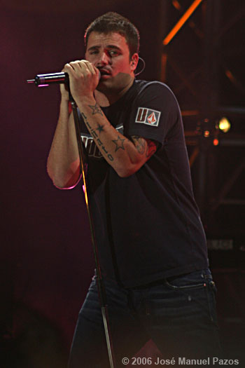 a man with tattoos on his arm singing into microphones