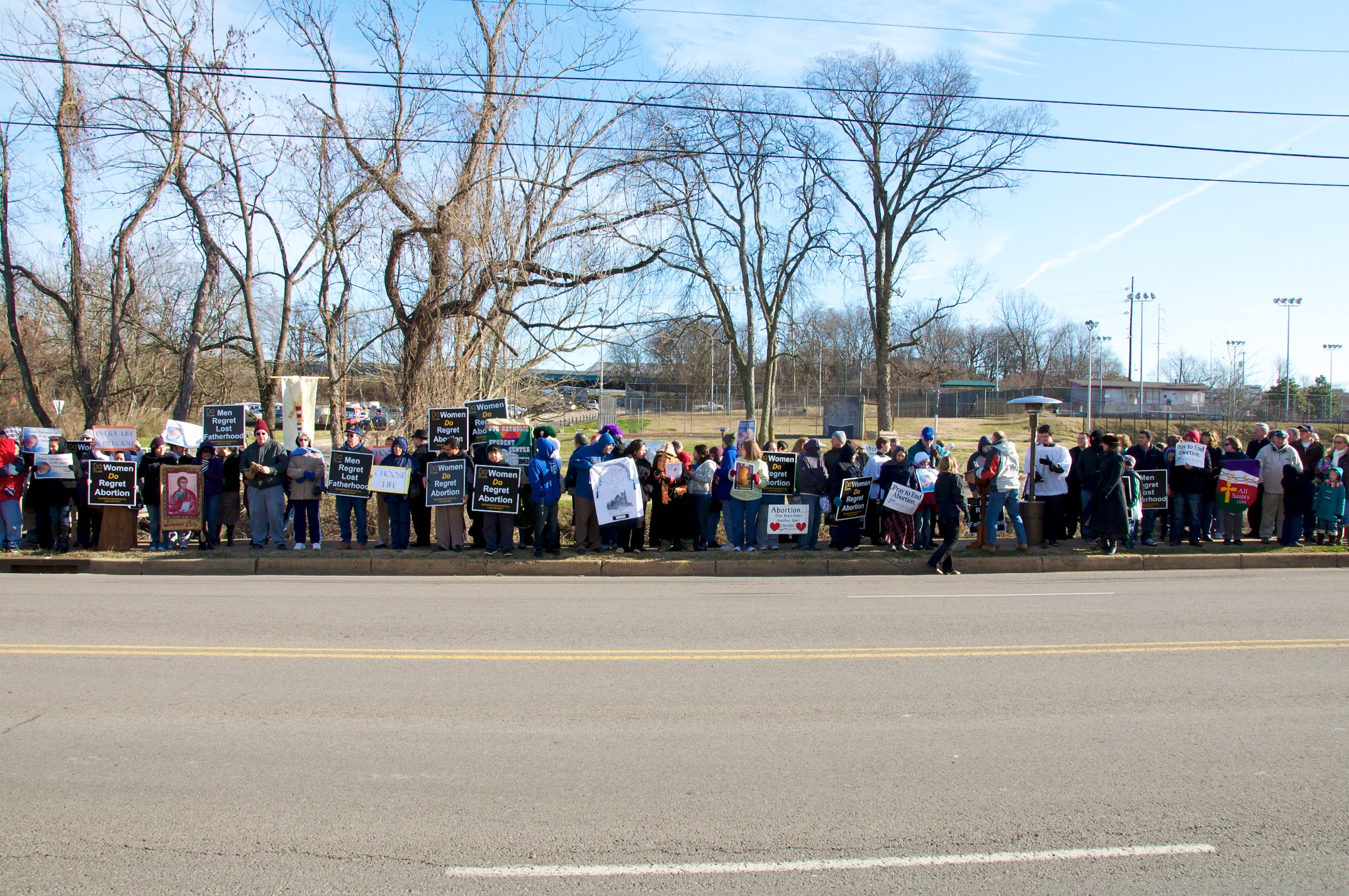 a group of people standing on the side of the road holding signs