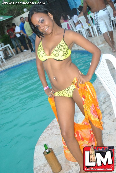 young woman in yellow and green bikini standing in water