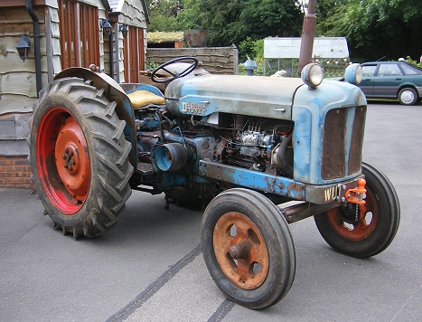 a vintage farm tractor sitting parked on the side of the road