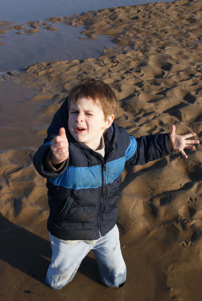 a small child in a jacket standing on a beach