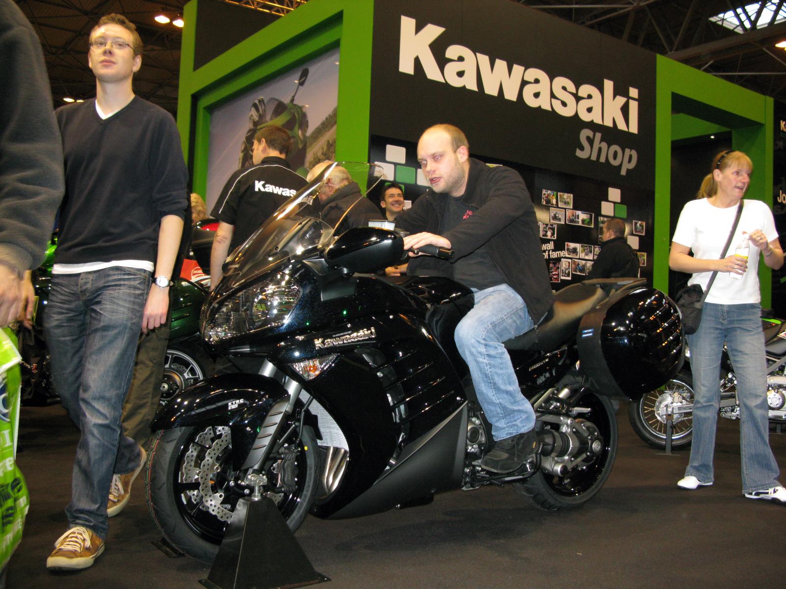 several people standing in front of a parked motorcycle