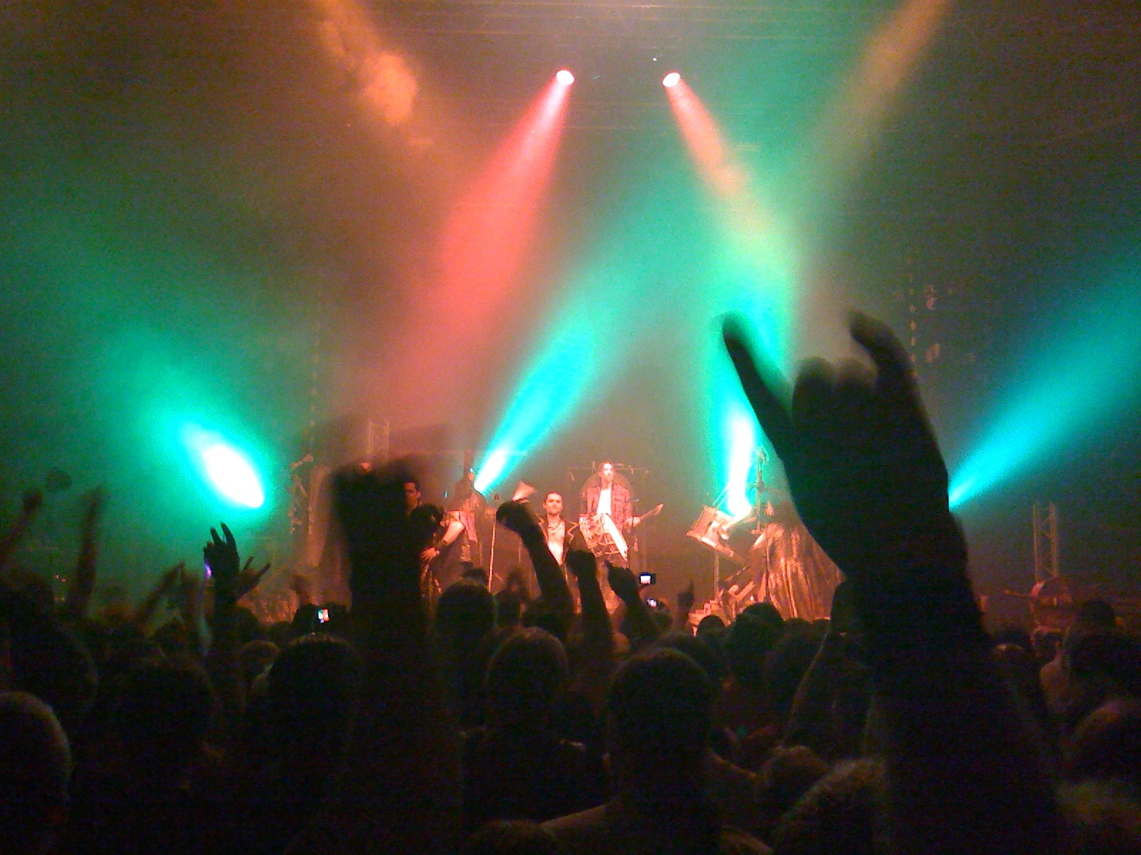 a concert on stage with many hands up in the air