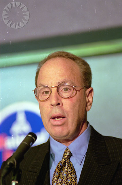 a man with glasses giving a speech at a podium