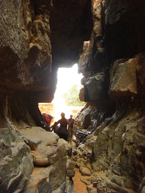 a man on the side of a mountain walking through a tunnel