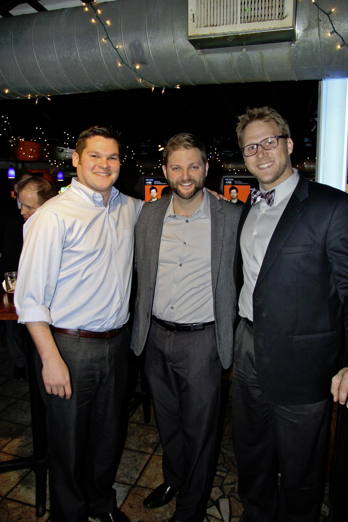 three men pose together while dressed up at an event