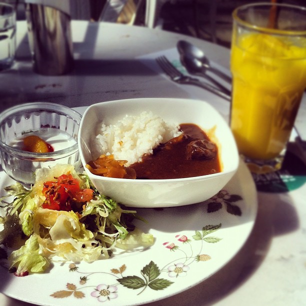plate of food with two sides of rice and a salad and orange juice