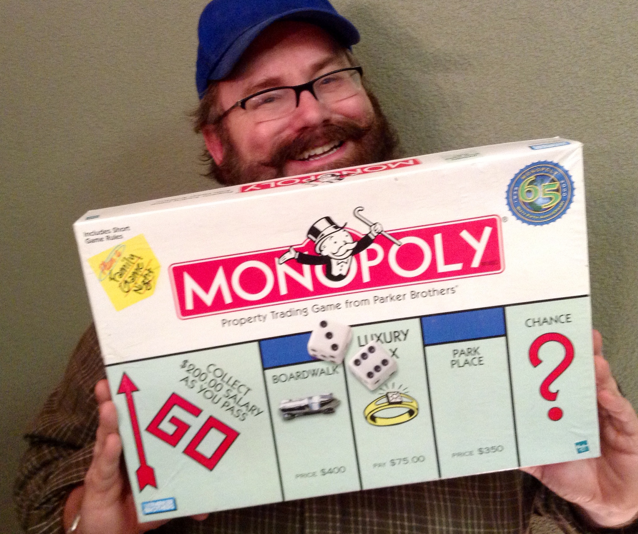 a man in a hat holding up a monopoly board
