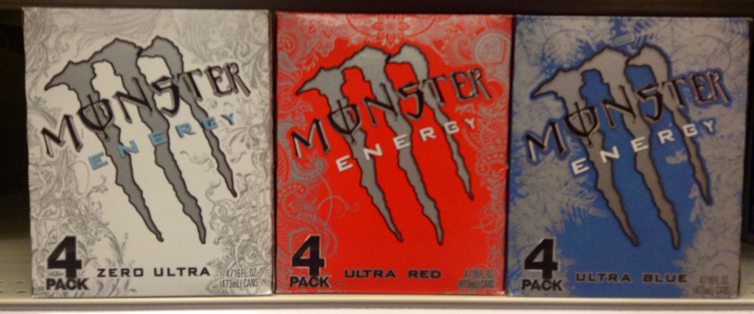 four packs of monster energy drink on a shelf