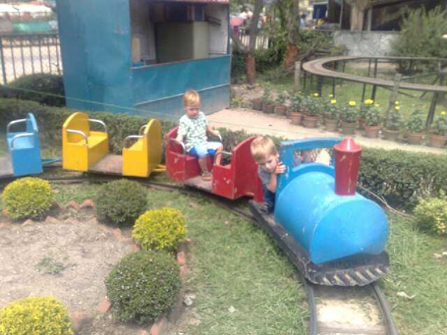 two toddlers playing in the train engine at an amut park