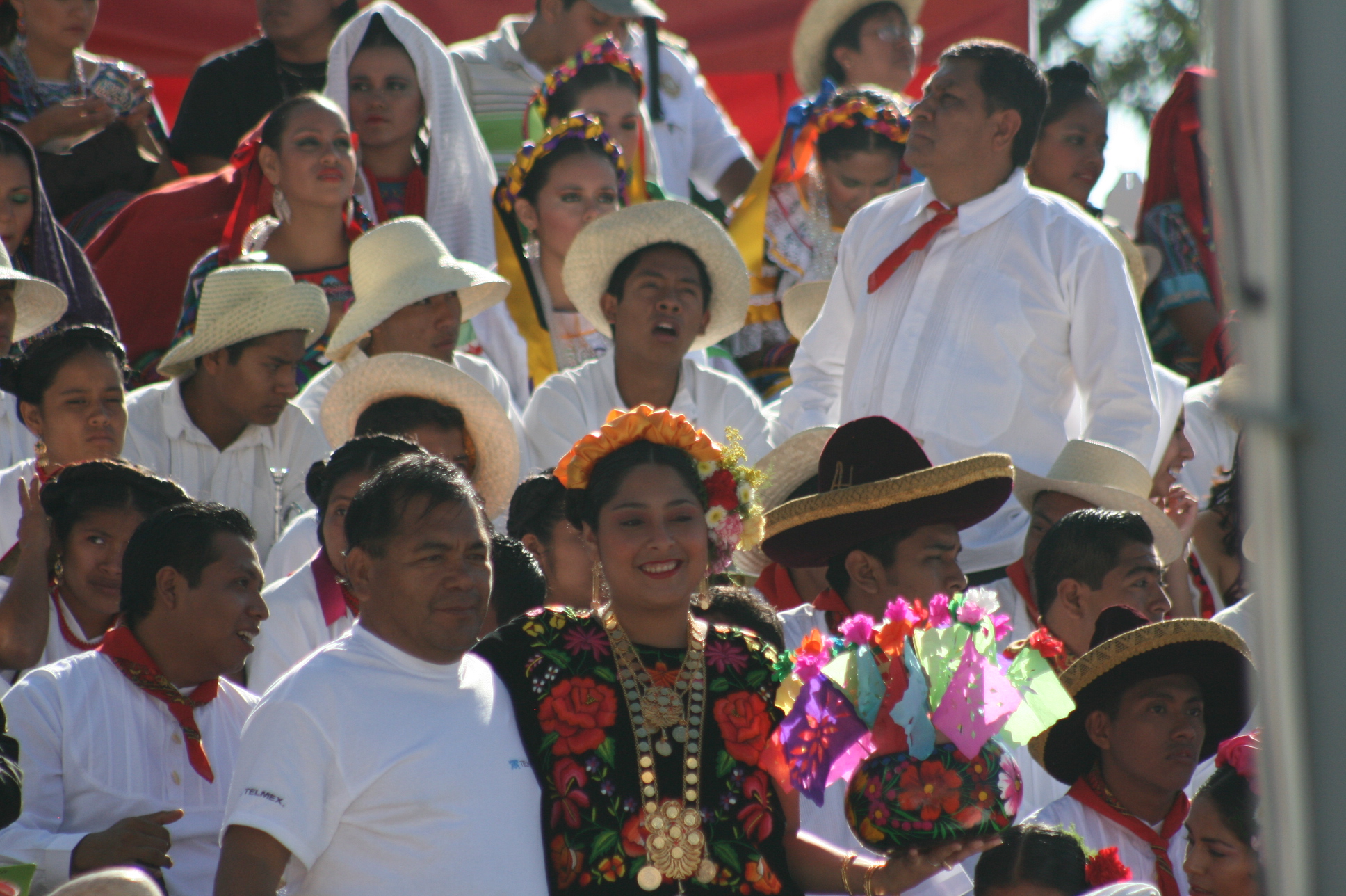a crowd of people with white shirts, white hats, and bright colored clothing