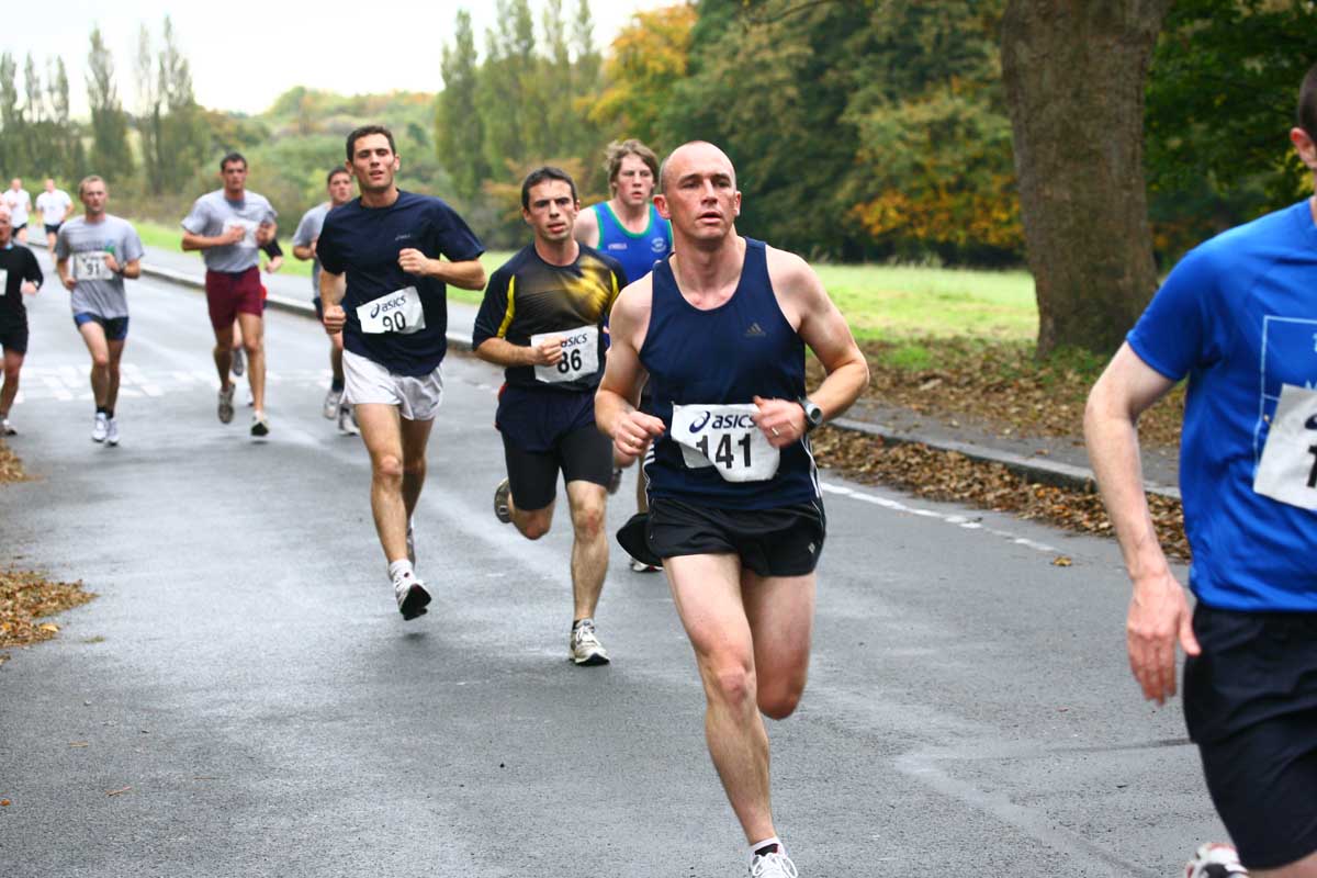 several people are running along a path, with trees and grass in the background