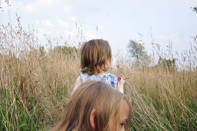 two young children walking through tall grass together