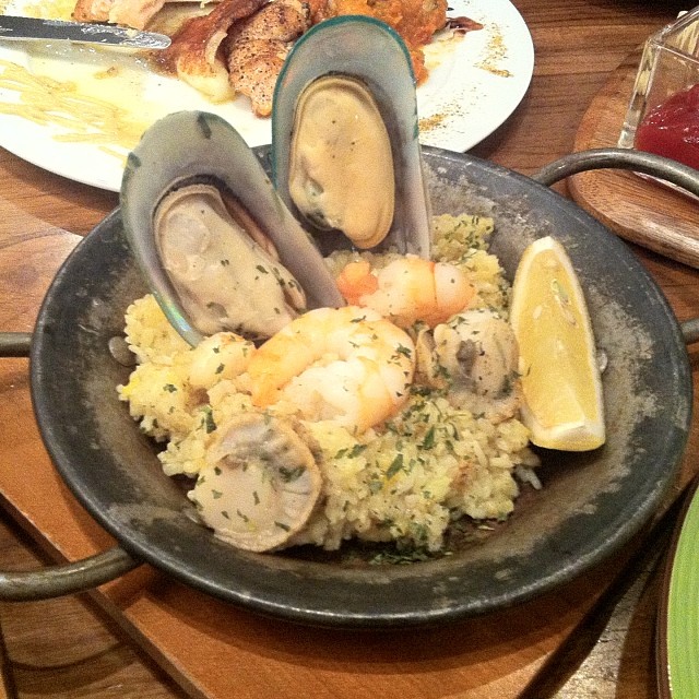 a plate of seafood and rice with lemon wedges