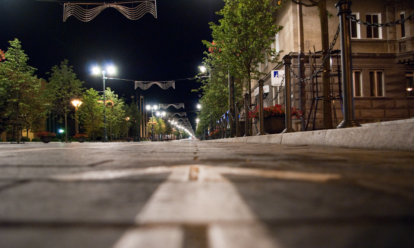 a deserted city street at night with several lit up buildings