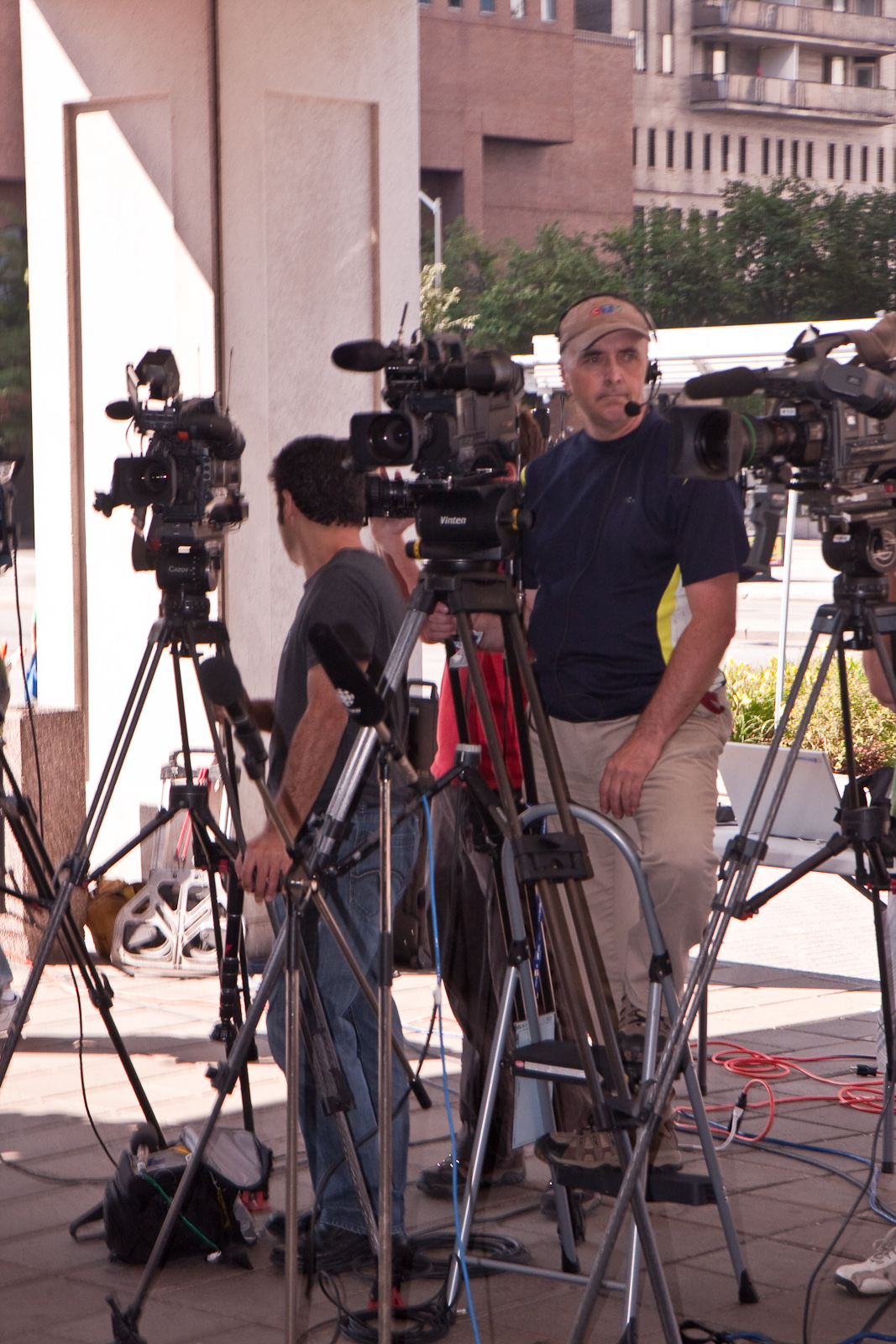 several cameras are lined up near a man in a hat