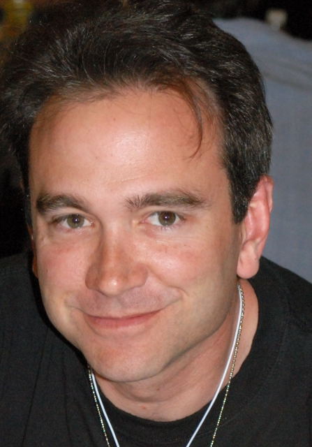 a man wearing a black shirt with a necklace on