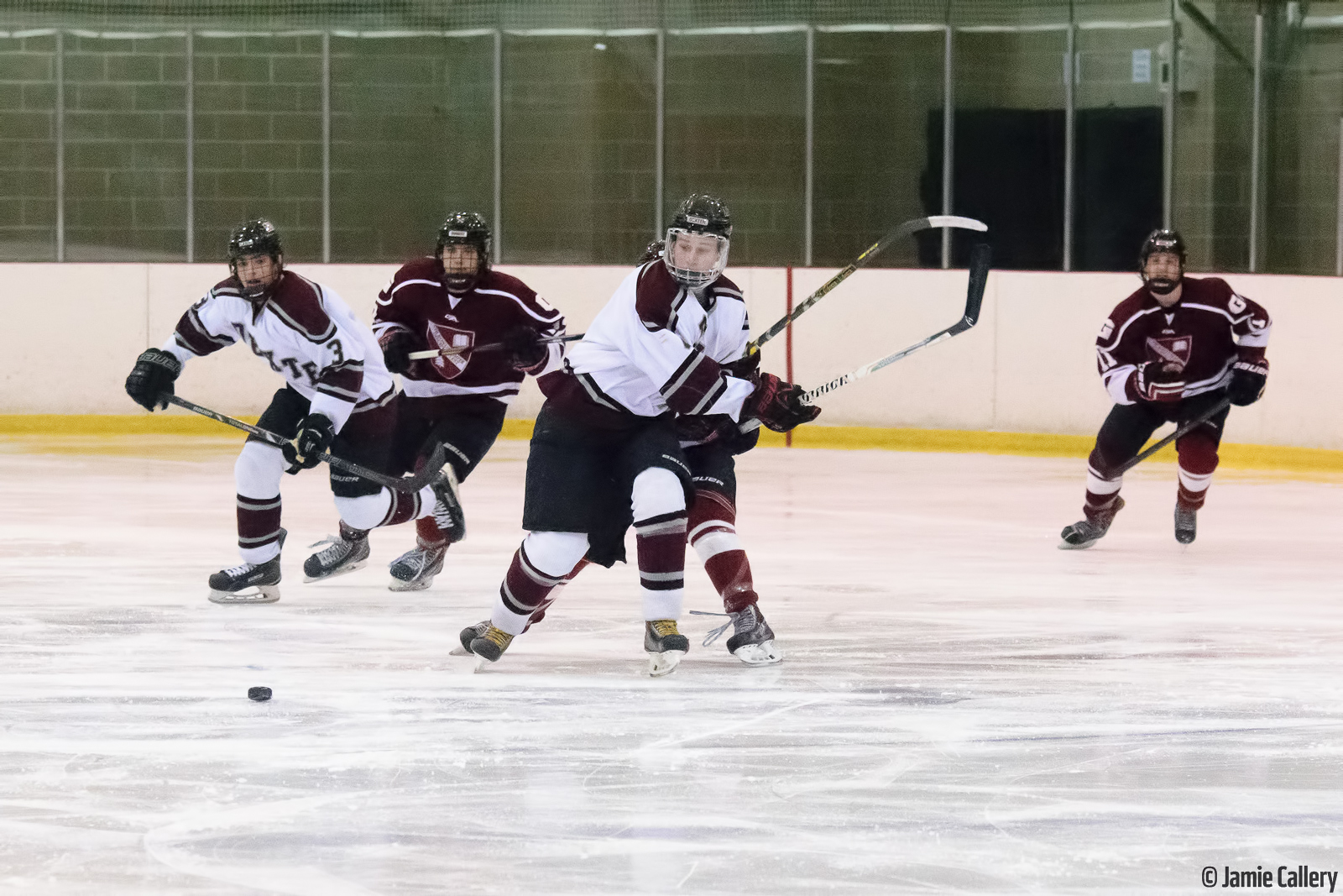 four people in uniform playing on a hockey rink